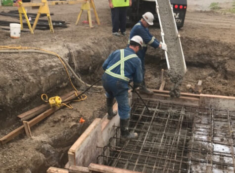 Workers filling footing with concrete