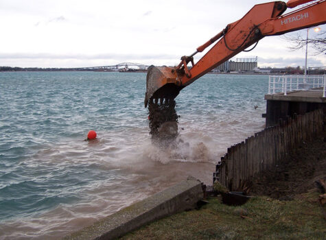 Excavator dumping backfill into waters edge