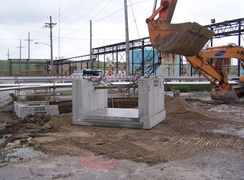 Preformed concrete being lifted by excavator