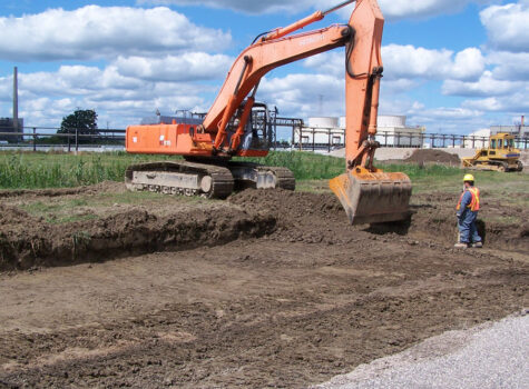 Excavator digging hole for containment area