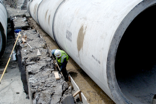 Man working beside large cement sewer pipe